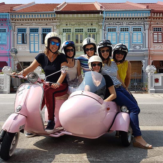 Visitors posing for a picture on Vespa sidecar Scooter